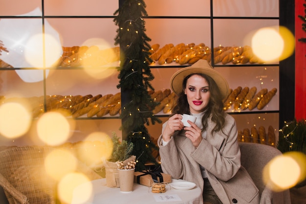 Une femme dans un café boit du café ou du thé Concept de Noël et du nouvel an