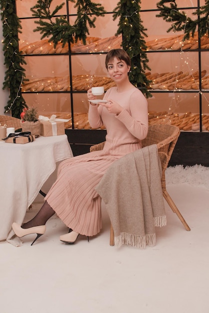 Une femme dans un café boit du café ou du thé. Notion de Noël et du nouvel an.