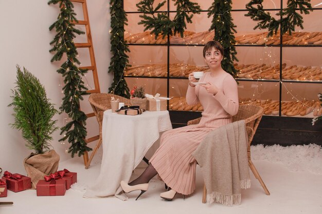 Une femme dans un café boit du café ou du thé. Notion de Noël et du nouvel an.