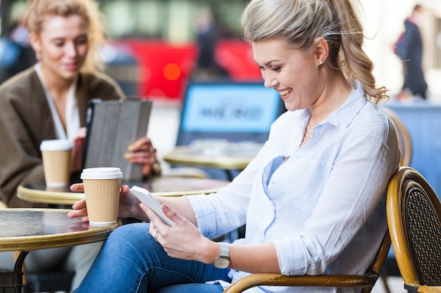 Femme dans un café en regardant son téléphone intelligent
