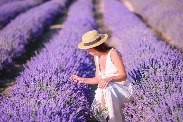 Femme dans le champ de fleurs de lavande en robe blanche et chapeau