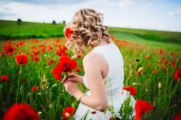 Femme dans un champ de fleurs rouges