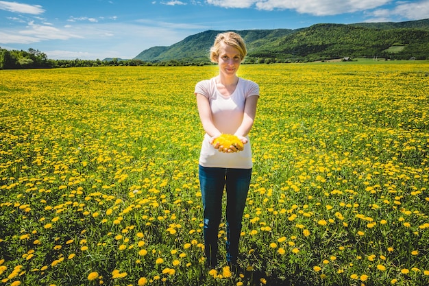 Femme dans un champ avec des pissenlits en fleurs