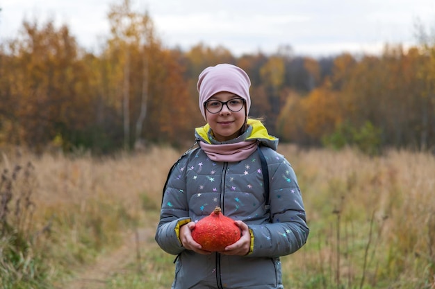 Une femme dans un champ tenant une citrouille rouge