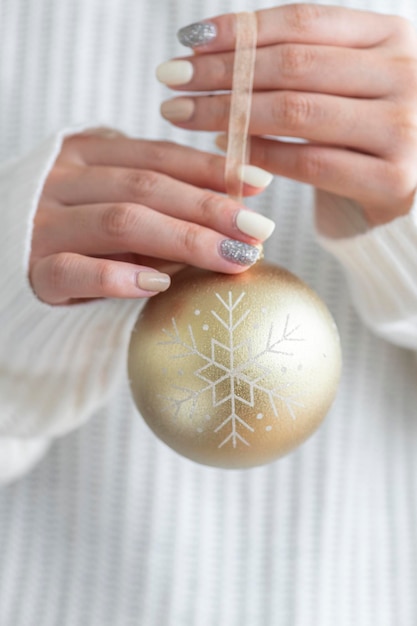 Femme dans un chandail blanc tenant une boule d'or