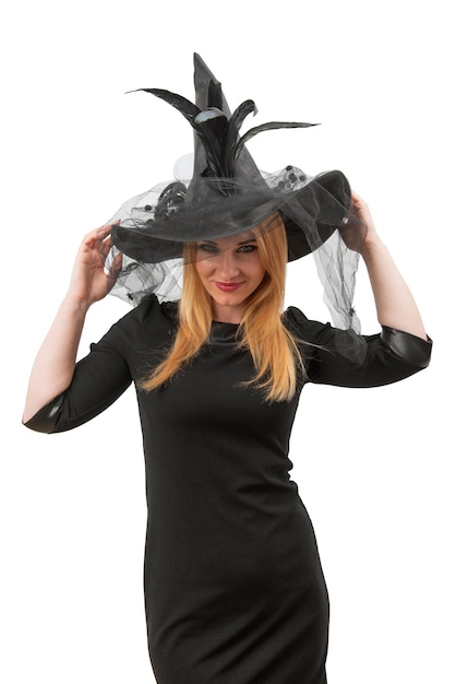 Femme dans un chapeau noir et une robe de sorcière regarde sournoisement la caméra fête d'Halloween fond blanc jeune sorcière cadre vertical