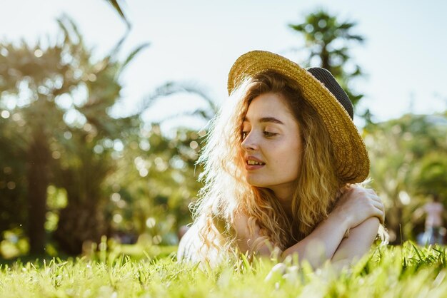 Photo une femme dans un chapeau de paille se trouve sur l'herbe dans un parc.