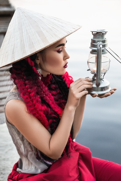 femme dans un chapeau de style asiatique avec une lanterne vintage