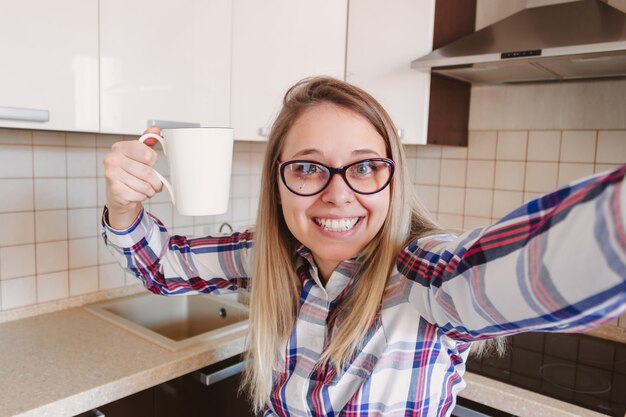 femme dans la chemise à carreaux et lunettes avec une tasse blanche