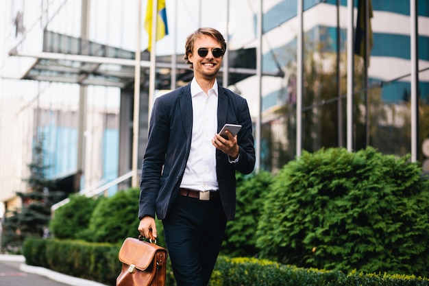 Femme dans un costume de bureau se promène dans le quartier financier portant un sac et un téléphone portable