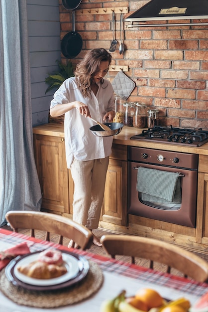 Femme dans la cuisine à la cuisinière en remuant les aliments dans une poêle à frire