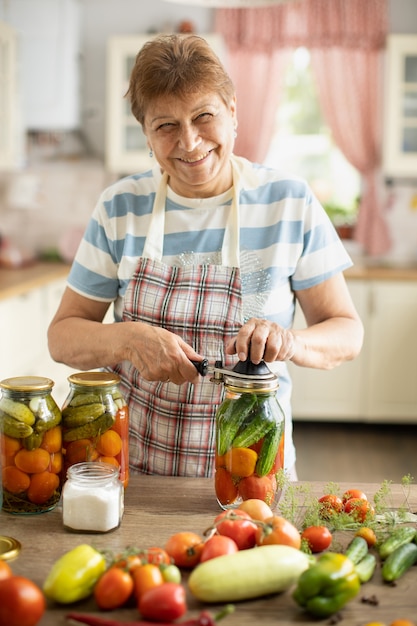 Femme dans la cuisine fait des cornichons à partir de tomates et de concombres, Femme dans la cuisine mettant des légumes en conserve