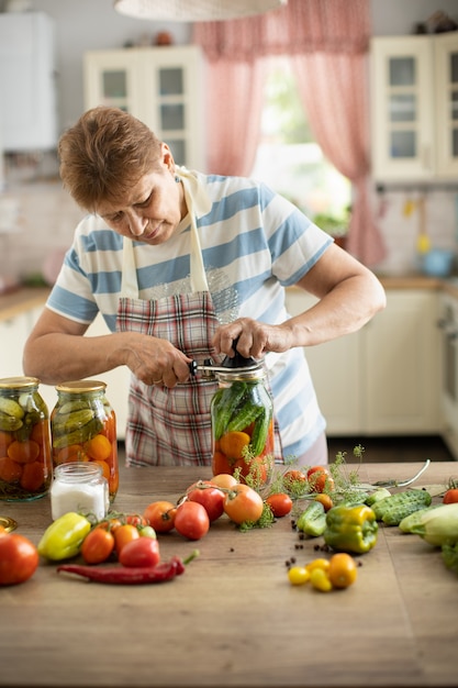 Femme dans la cuisine fait des cornichons à partir de tomates et de concombres, Femme dans la cuisine mettant des légumes en conserve