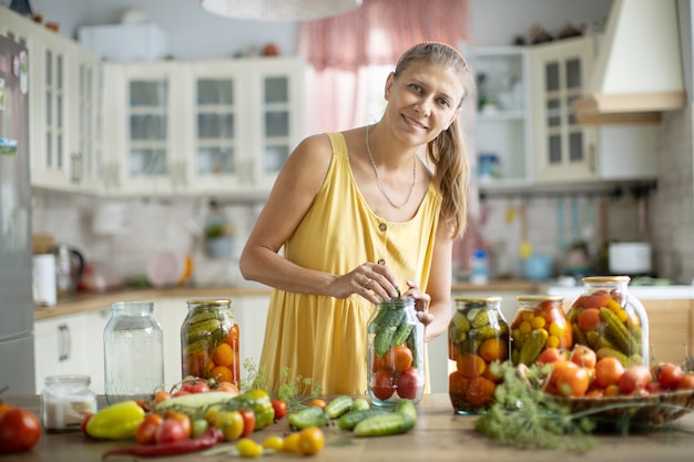 Femme dans la cuisine mettant des légumes en conserve