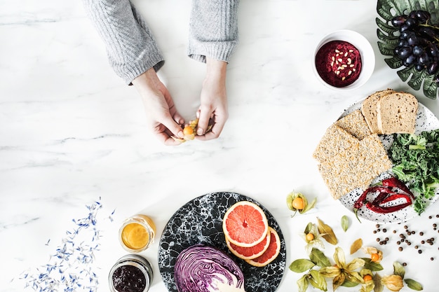 Femme dans la cuisine et sa sélection d'aliments sains : fruits, légumes, super aliments, graines, espace de copie d'arrière-plan en marbre.