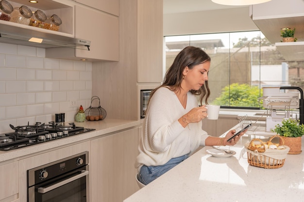 Femme dans une cuisine spacieuse et neuve prenant son petit déjeuner