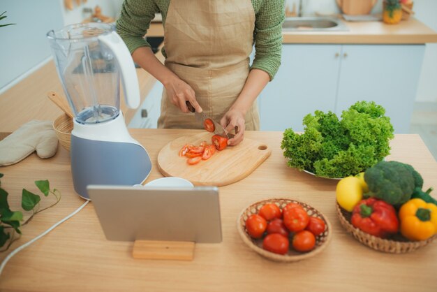 Femme dans la cuisine à la suite de la recette sur tablette numérique