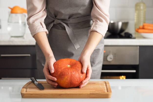 Une femme dans la cuisine tient une citrouille dans ses mains