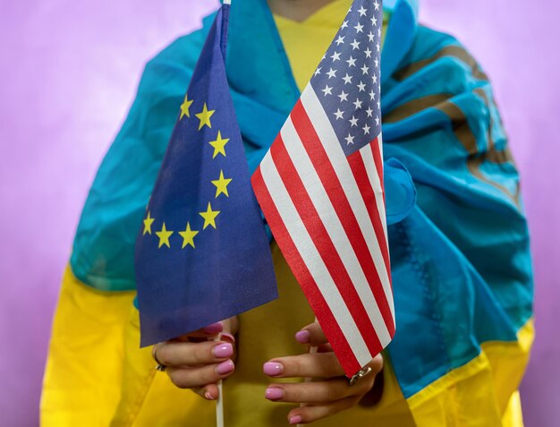 Une femme dans le drapeau national de l'ukraine tient le drapeau de l'ue et des états-unis La guerre de l'Ukraine contre la Russie est un pays terroriste assisté par des pays alliés