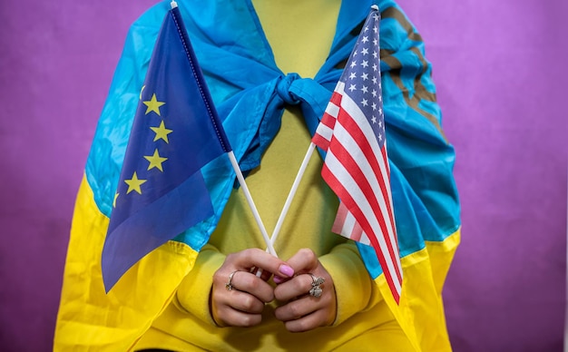 Une femme dans le drapeau national de l'ukraine tient le drapeau de l'ue et des états-unis La guerre de l'Ukraine contre la Russie est un pays terroriste assisté par des pays alliés
