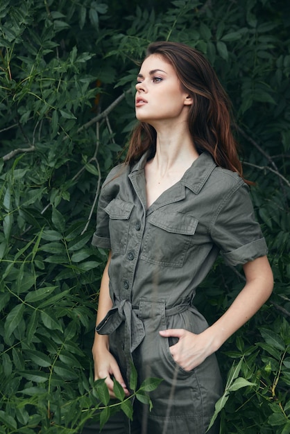 Femme dans la forêt La main dans la poche de la salopette regarde de côté l'arrière-plan