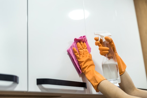 Femme dans des gants en caoutchouc nettoyant la surface sale dans la cuisine. travaux ménagers