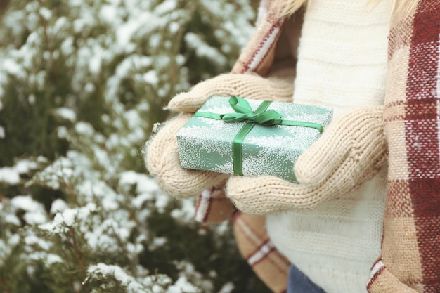 La femme dans les gants tricotés tient la boîte-cadeau