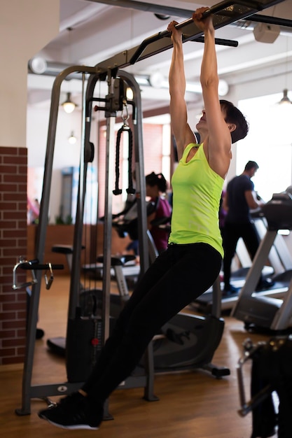 La femme dans le gymnase secoue la presse sur la barre