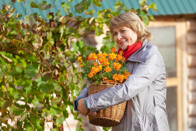 Une femme dans le jardin d'automne récolte et enlève les ordures.