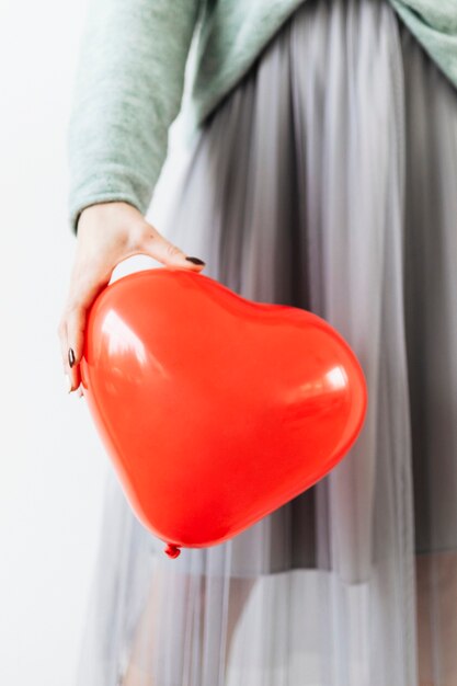 Femme dans une jupe en mousseline grise montrant un ballon rouge