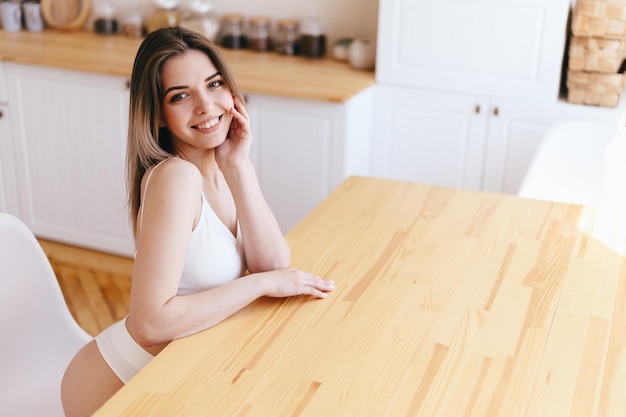 femme, dans, lingerie, sourire, séance table bois, flou, cuisine, dans, fond