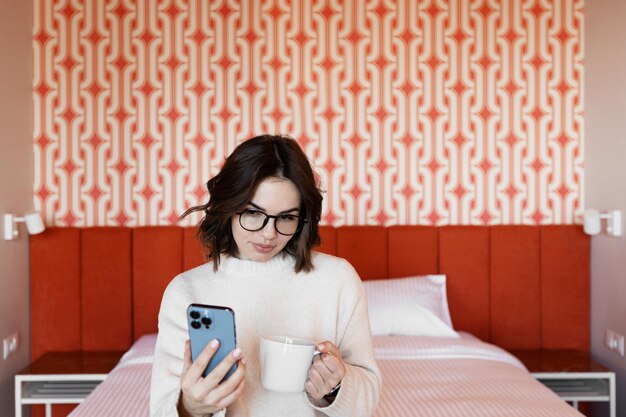 Une femme dans un lit avec un téléphone à la main