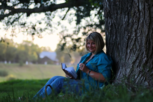 Femme dans le livre de lecture d'arbre de parc