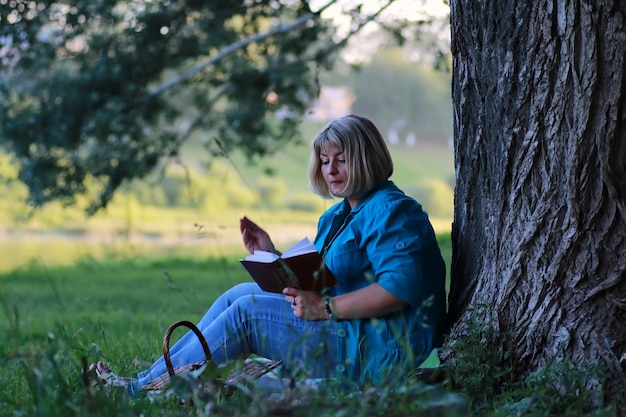 Femme dans le livre de lecture d'arbre de parc