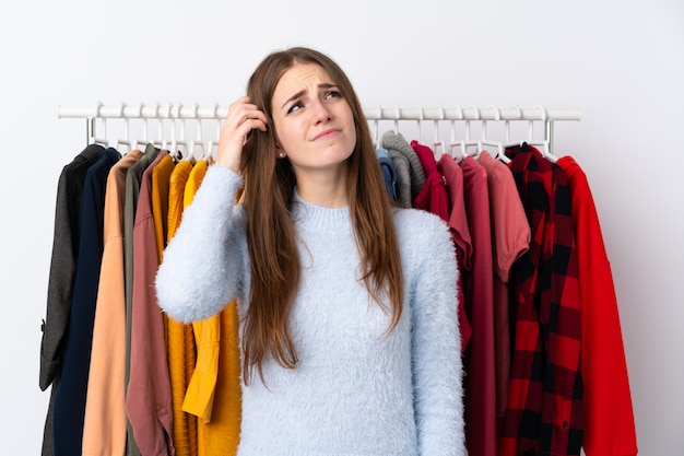 Femme dans un magasin de vêtements avec beaucoup de vêtements derrière