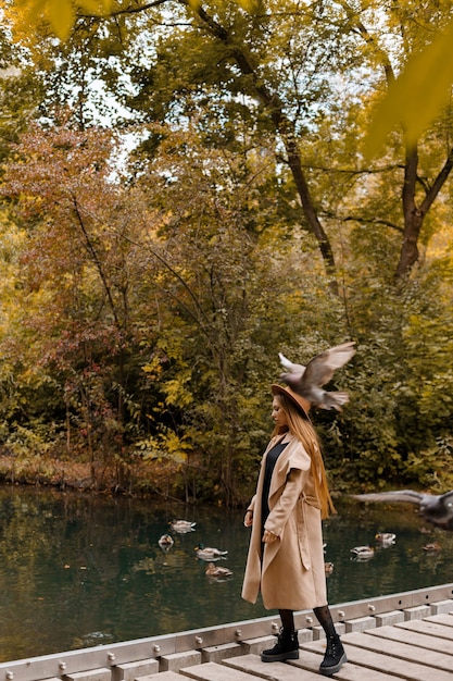 Une femme dans un manteau d'automne dans un parc de la ville à l'automne lors d'une promenade