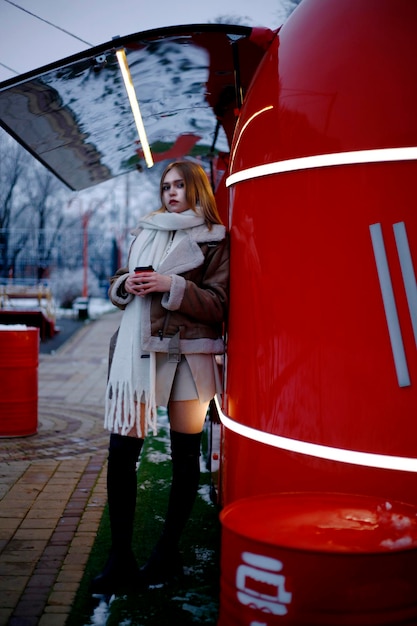 une femme dans un manteau brun tient une tasse de café