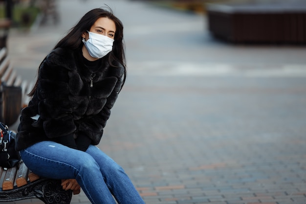 Femme dans un masque assis sur un banc