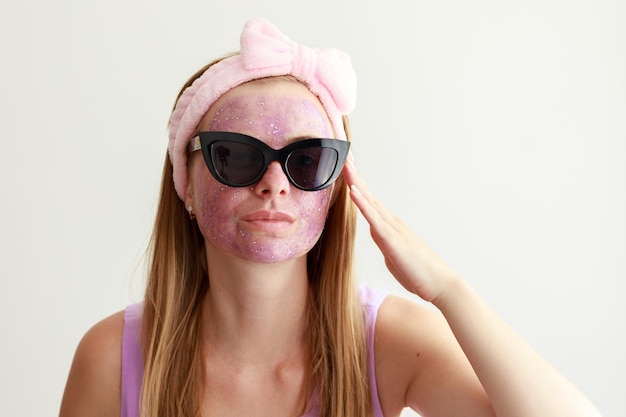 Femme dans un masque cosmétique sur son visage sur fond blanc procédures de beauté