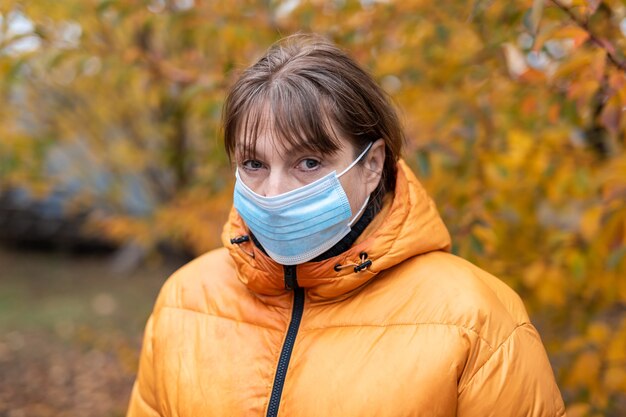 Femme dans un masque médical dans le parc de l'automne