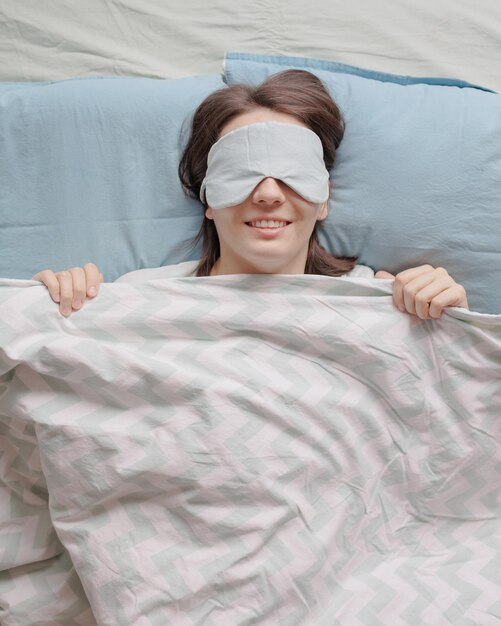 Une femme dans un masque de sommeil est allongée dans son lit et dort une femme européenne heureuse avec la santé mentale et