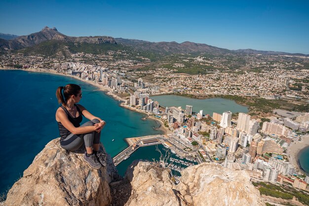 Femme dans les montagnes assis sur un rocher en regardant la ville