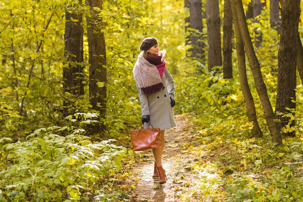 Femme dans le parc automne posant avec valise