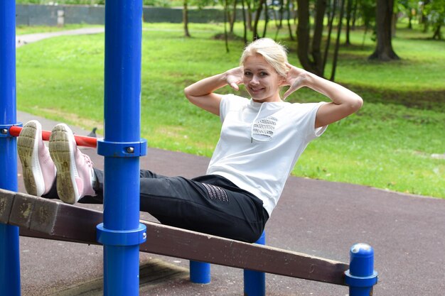 femme dans le parc est engagée dans la gymnastique fille sur barre horizontale gymnastique à l'extérieur