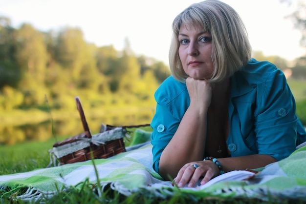 Femme dans le parc avec livre sur l'herbe