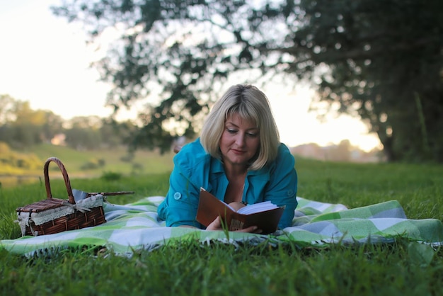 Femme dans le parc avec livre sur l'herbe