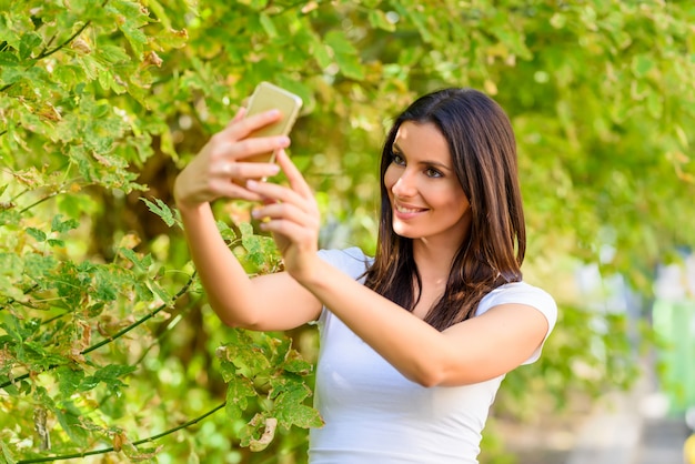 Une femme dans un parc prenant un selfie avec son smartphone