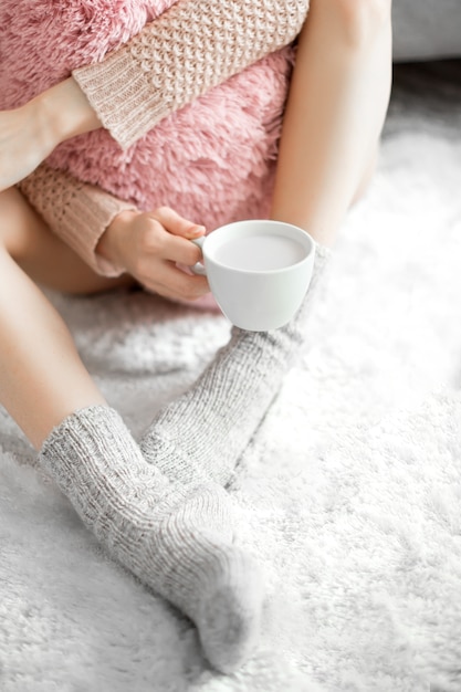 Femme dans une pièce confortable avec une tasse de cacao à la main.