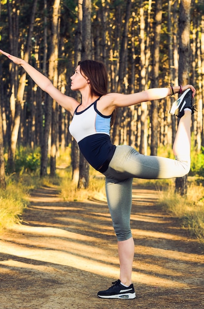 Femme dans la position de danseur dans le paysage forestier