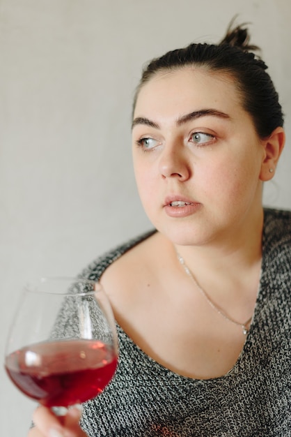 Femme dans un pull gris avec un verre de vin rouge